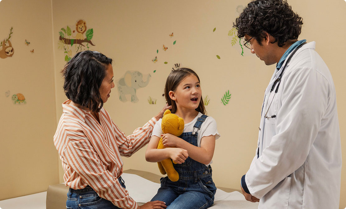 Doctor talking with a smiling girl and her mother