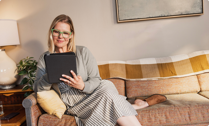 Woman reviewing a tablet on a couch.